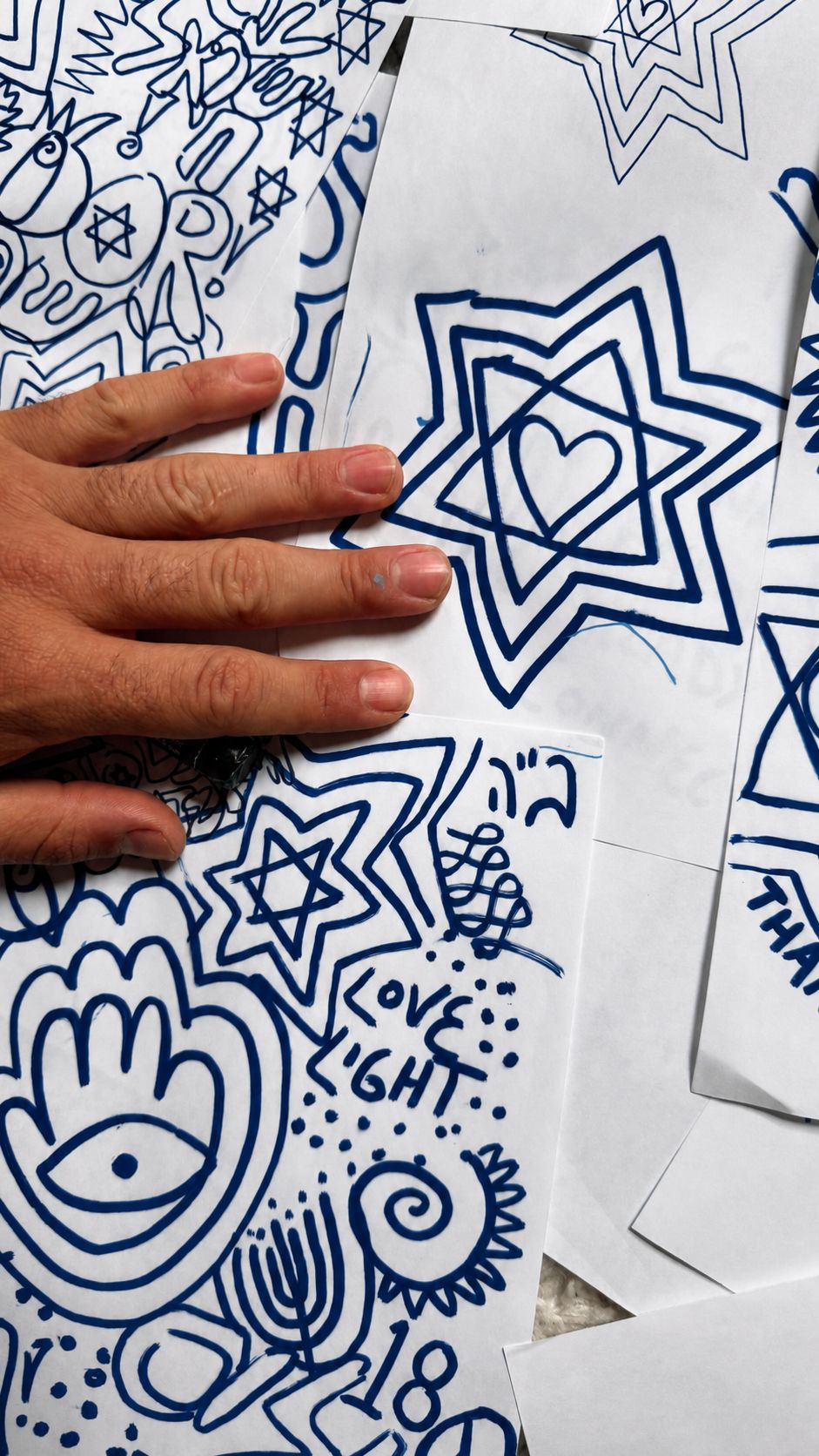 The artist's hand over navy marker sketches
